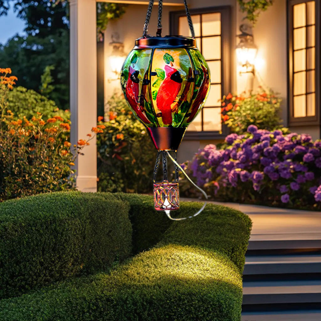 Decorative hanging solar light with colorful design in a garden setting.
